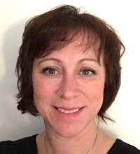 Mörkhårig Åsa Cajander ler in i kameran, porträtt