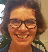 ingela målqvist, en glad kvinna med brunt hår och galsögon ler stort in i kameran.