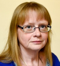 Porträtt Carina Lenngren med glasögon, ljus bakgrund, Arbetsmiljölyftet