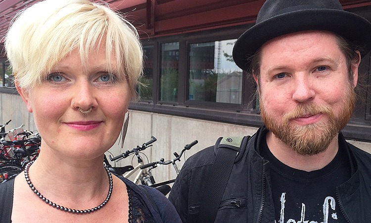Anna-Carin Fagerlind Ståhl och Christian Ståhl. Anna-Carin i blond page och näsring, Christian i skägg och svart hatt. Står utomhus med ett cykelställ i bakgrunden.