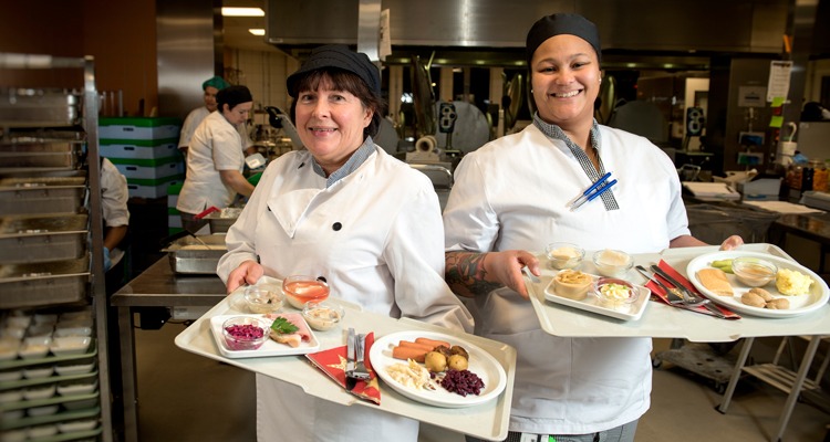 Tina Snöberg, servicechef på måltid Regionservice, och Julie Bettle, kock, står med varsin bricka och visar upp julmaten som ska serveras för sjukhusets patienter.