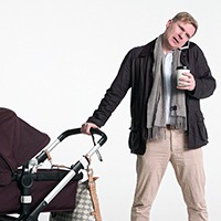Man med barnvagn i ena handen och mobiltelefon klämd vid örat.