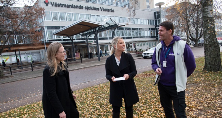 Tre personer står och pratar utanför västmanlands sjukhus. De håller lite avstånd till varandra.