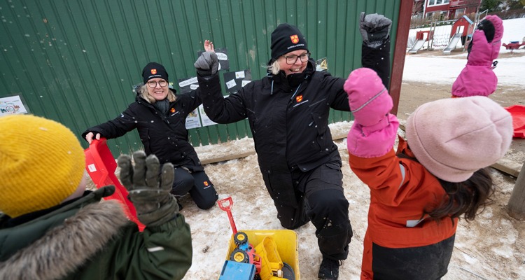 Förskolepersonal och barn på förskolegården
