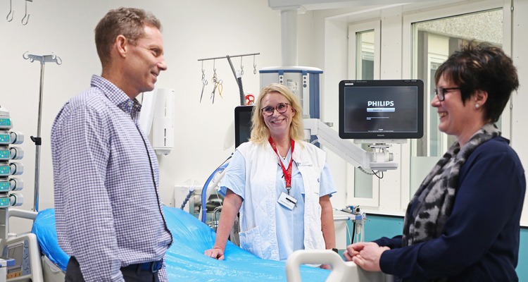 Hr, chef och sjuksköterska står vid en tom patientsäng