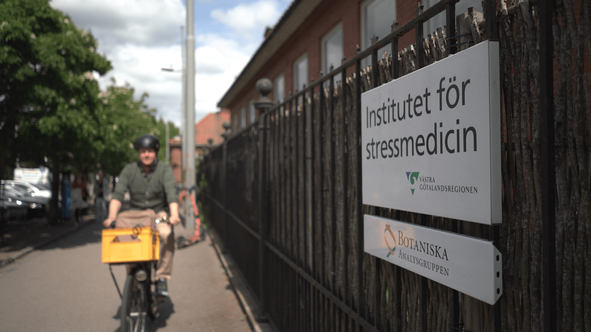 Forskaren Magnus Åkerström på cykel framför institutet för stressmedicin