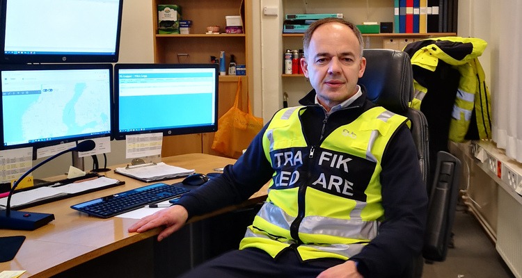 En trafikledare sitter vid ett skrivbord och tittar mot kameran