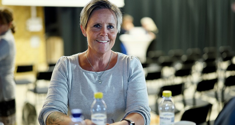 Kvinna med konferenslokal i bakgrunden.