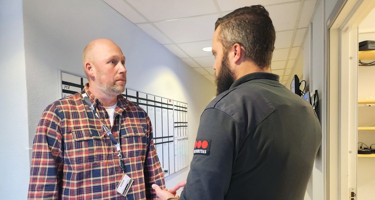 Säkerhetssamordnaren står i en korridor och pratar med en vakt