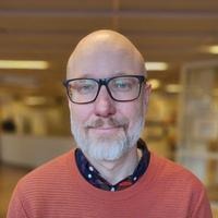 Porträttbild av Henrik Hultman stående i en sjukhuskorridor.
