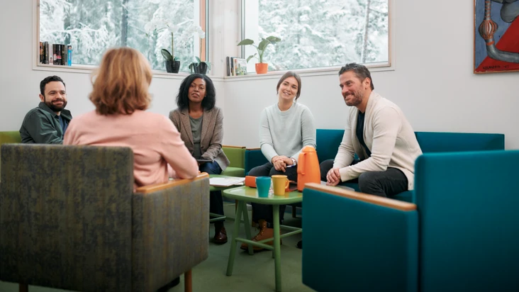 En arbetsgrupp sitter i en soffa och pratar friskfaktorer.
