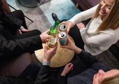 en rgupp människro sedda uppifrån, som sitter och skålar med ölburkar och ölflaskor