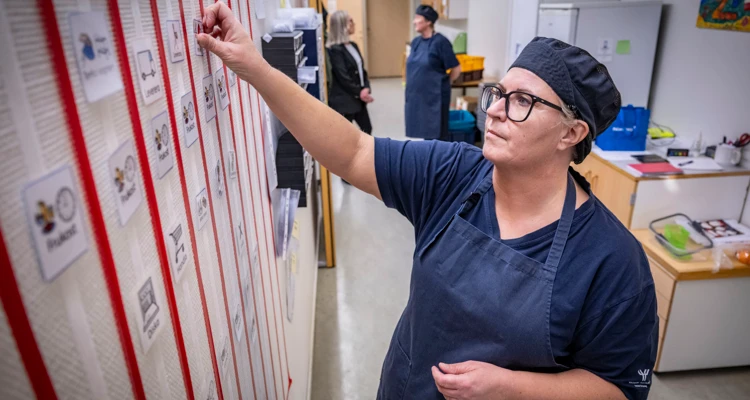 Johanna Karlsson ordnar schemat med bildstöd på väggen.