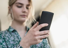 En kvinna som håller en mobiltelefon i handen.