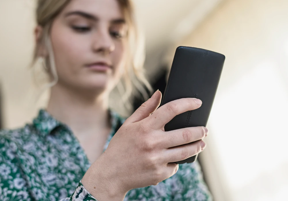 Närbild på kvinna som pratar med mobiltelefon hon håller i handen.