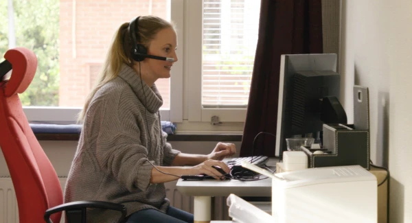 En kvinna sitter vid ett skrivbord och använder en dator.
