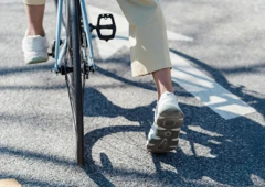 Cykelhjul och två fötter med sommarskor, allt belyst av solsken.