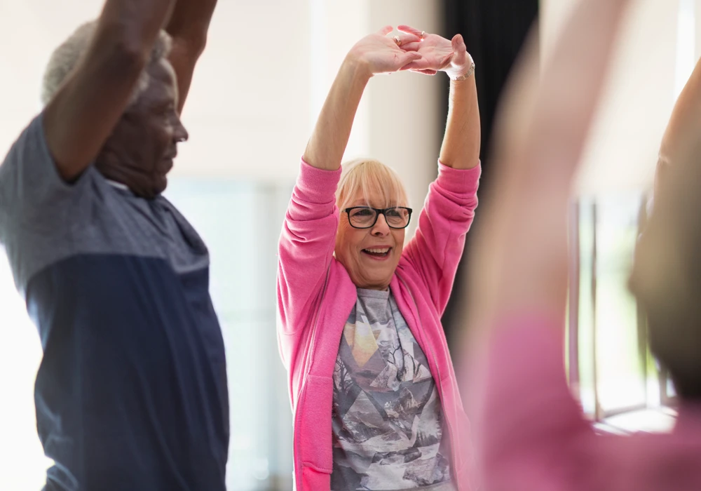 Två glada personer stretchar för att motverka stel nacke och ont i nacke och skuldror, så kallad askungenacke.
