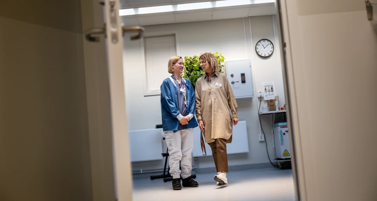 Två kvinnor står och pratar under dagsljuslamporna.