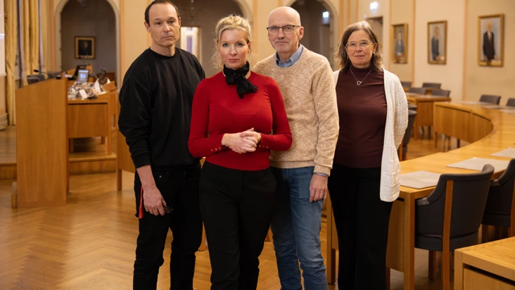 Fyra personer ur Eskilstuna kommuns ledning och politiska nämnder står i ett stort mötesrum.