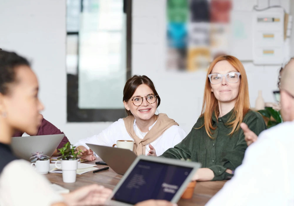 Gruppkommunikation mellan personer som sitter runt ett träbord.