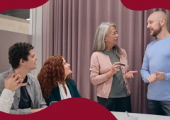 Fyra personer står i ett mötesrum och pratar.