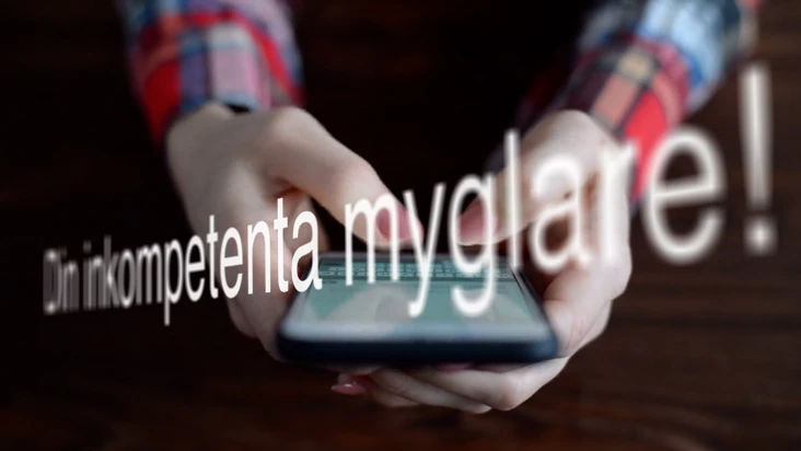 En person håller en telefon, och ovanför telefon står texten 