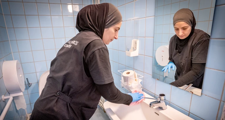 Lokalvårdare städar handfat.