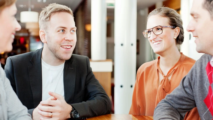 En grupp personer sitter och pratar vid ett bord.