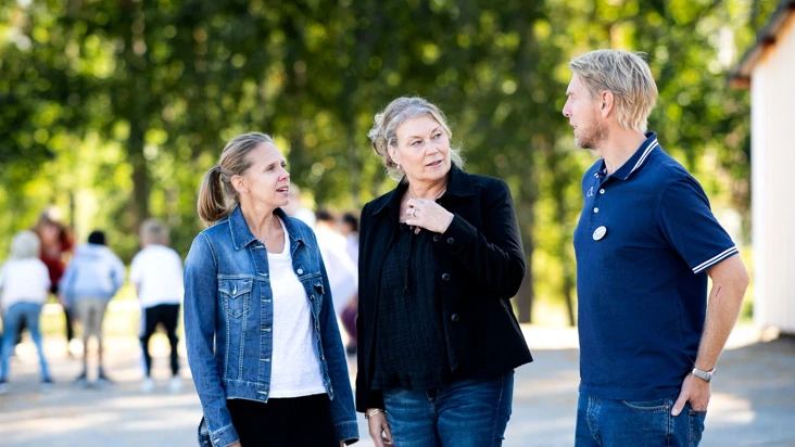 Tre personer står på en skolgård.