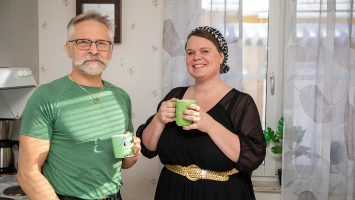 En man och en kvinna står med kaffekoppar och tittar mot kameran.