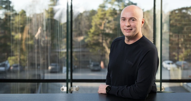 Stefan Jansson, vd i Kraftstaden står vid ett bord med fönster i bakgrunden.