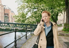 En kvinna går längs en gata medan hon pratar i mobiltelefon.