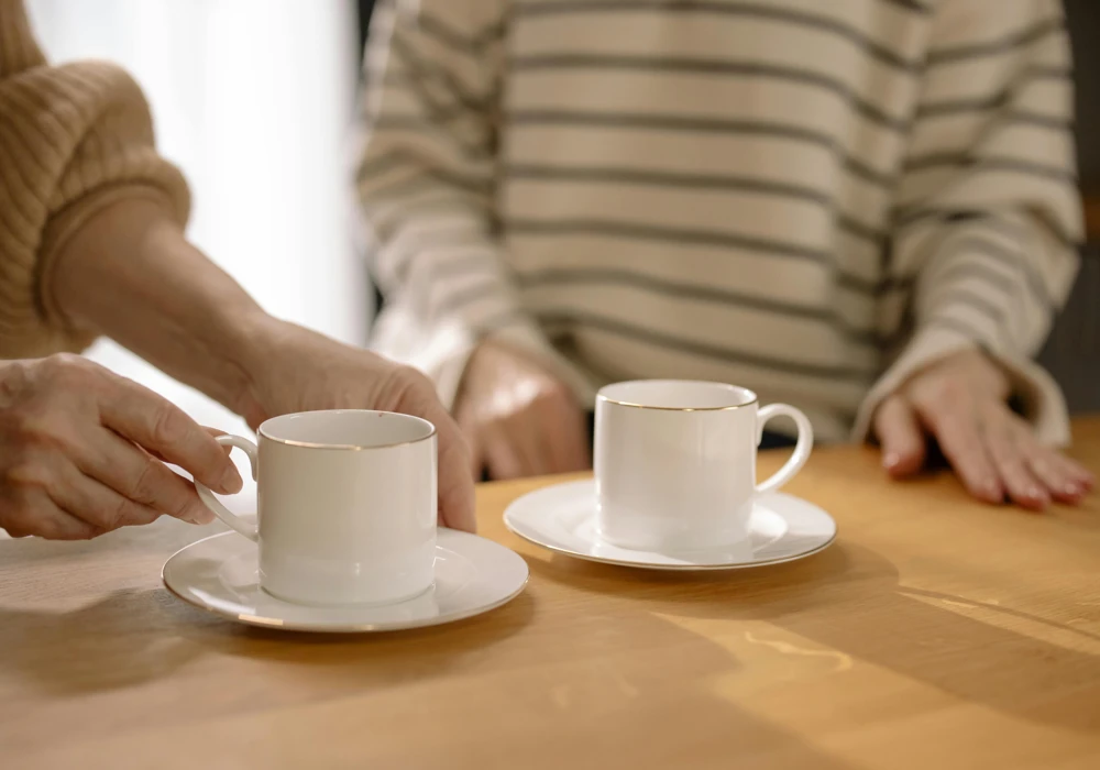 Två kaffekoppar på ett bord och en hand som håller i ena.