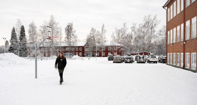 En man går över en snöig skolgård.
