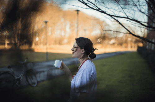 Kvinna står utomhus och dricker kaffe.