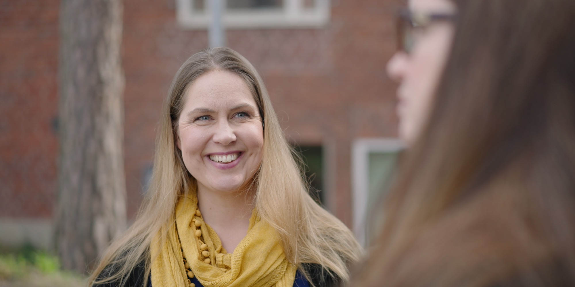 Två kvinnor står utomhus och pratar.
