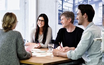 En grupp människor som sitter runt ett träbord.